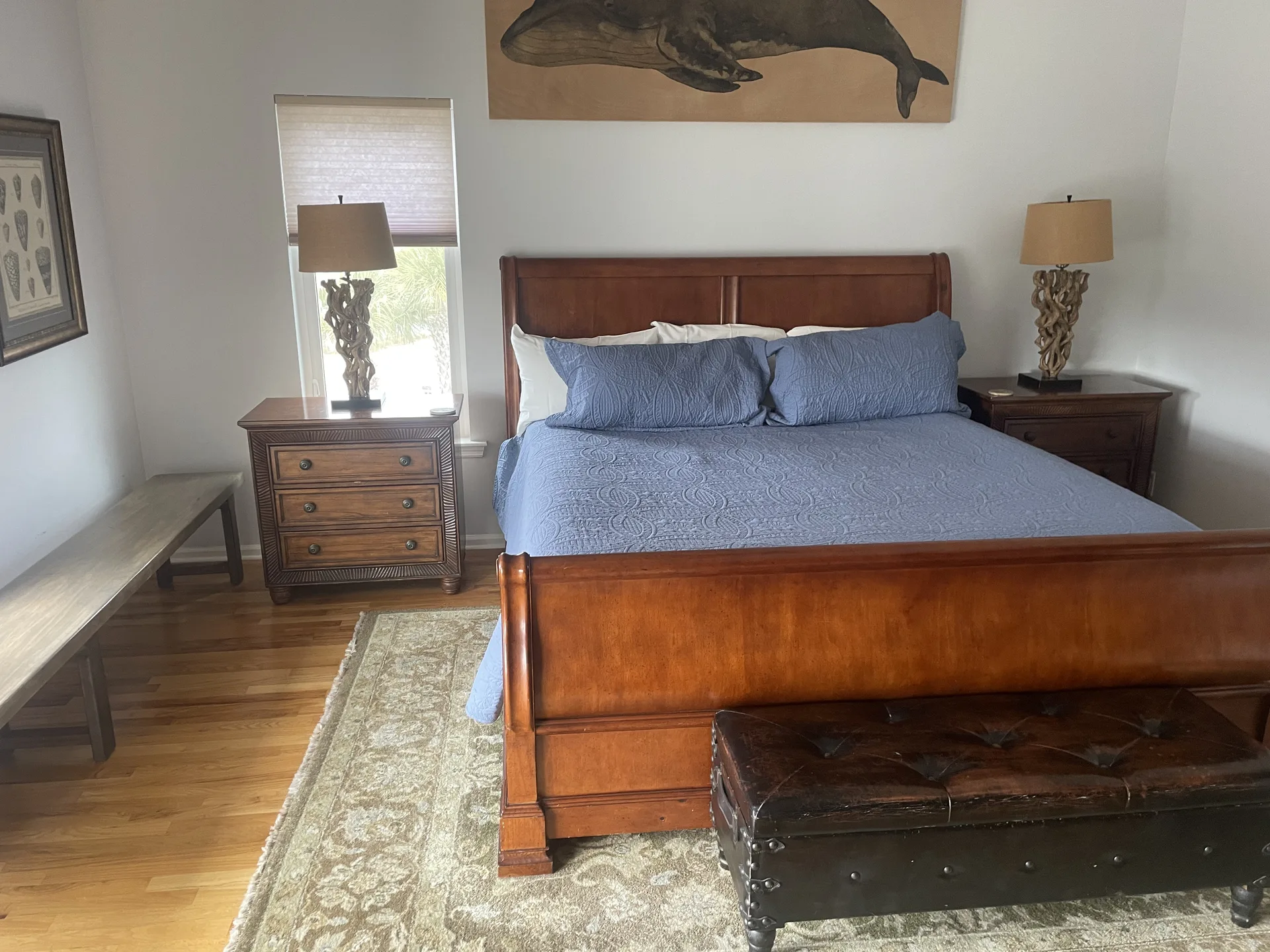 Master bedroom with cherry sleigh bed, whale artwork, and driftwood lamps