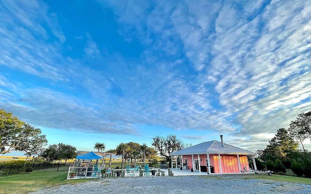 The full compound at blue hour — salmon-pink playhouse with turquoise chairs and dramatic sky