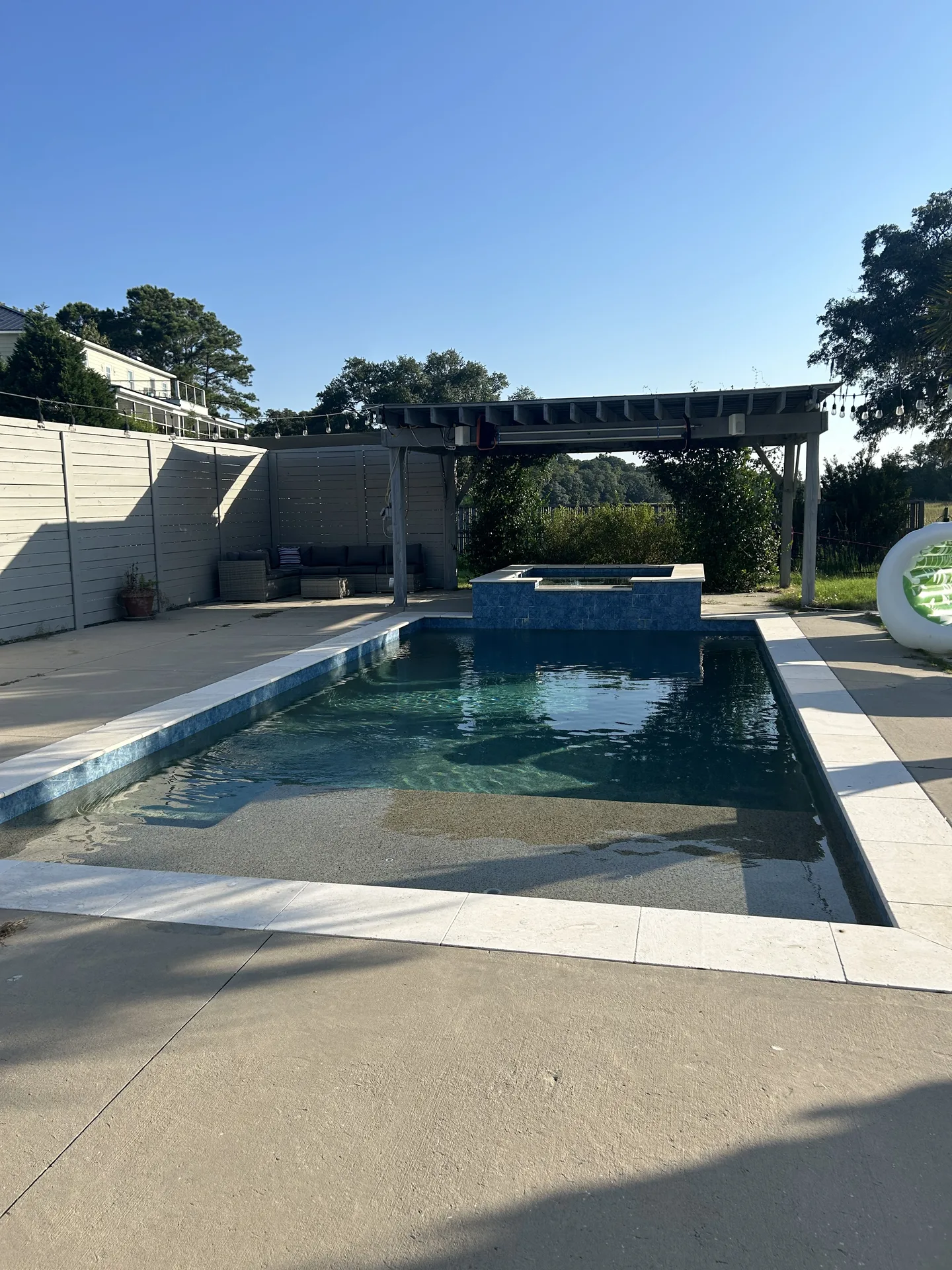 Saltwater pool with raised spa from the pergola — lounge chairs and turquoise water