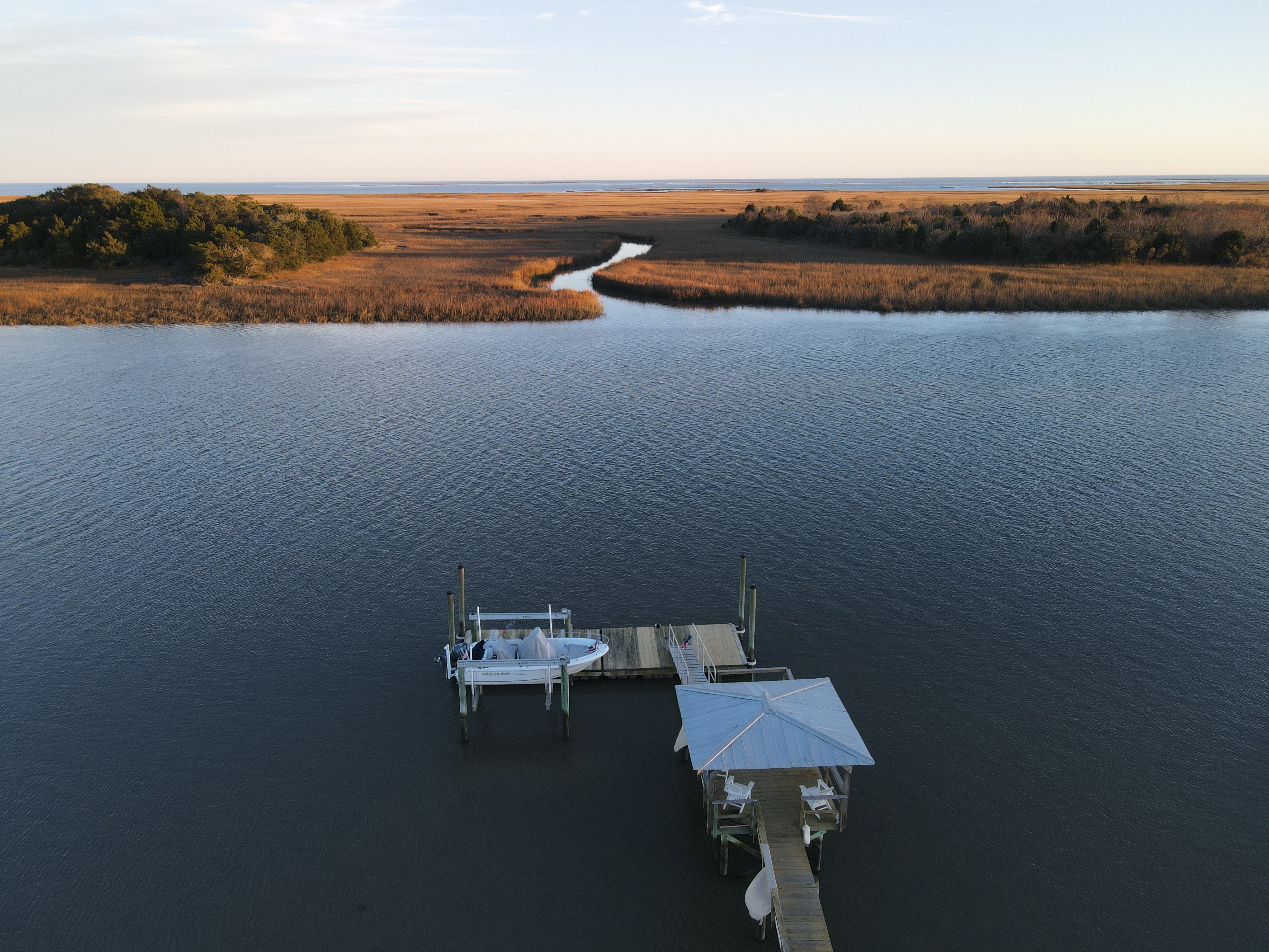 Aerial drone view of private dock stretching into Graham Creek at golden hour with endless Intracoastal marsh