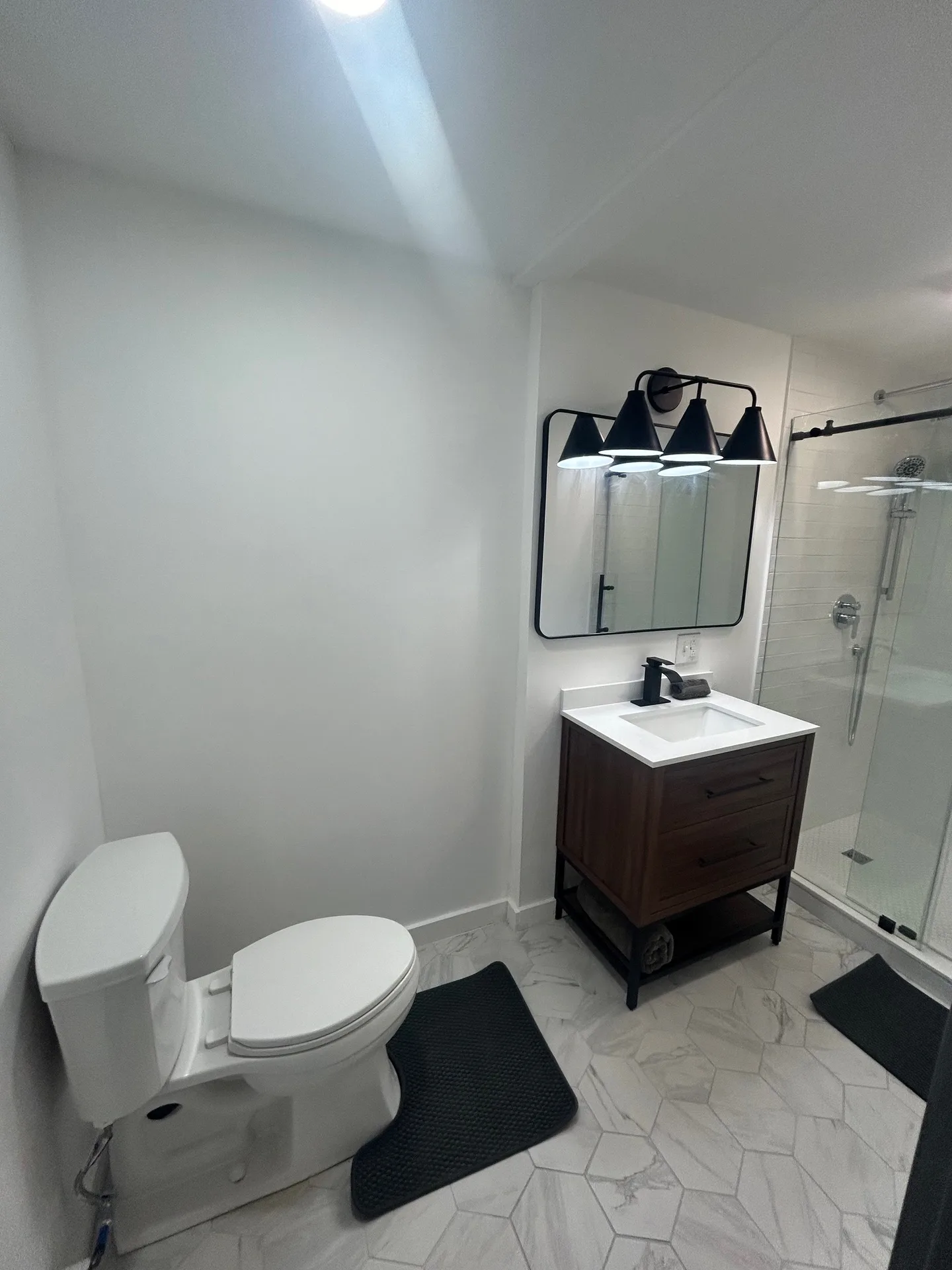 Bathroom with dark walnut vanity, matte black fixtures, and hexagonal marble floor