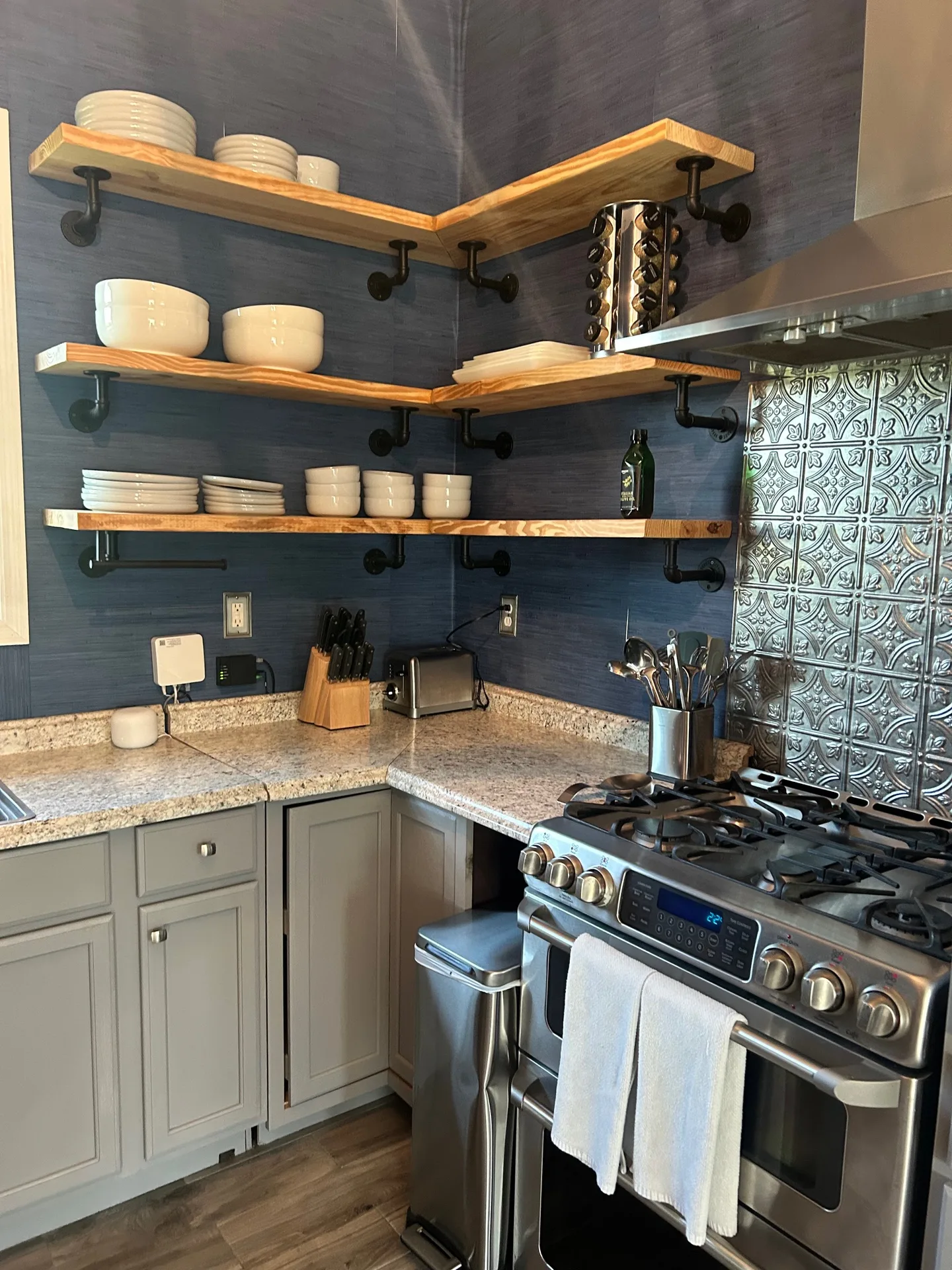 Kitchen corner with gas range, pressed tin Victorian backsplash, and navy walls
