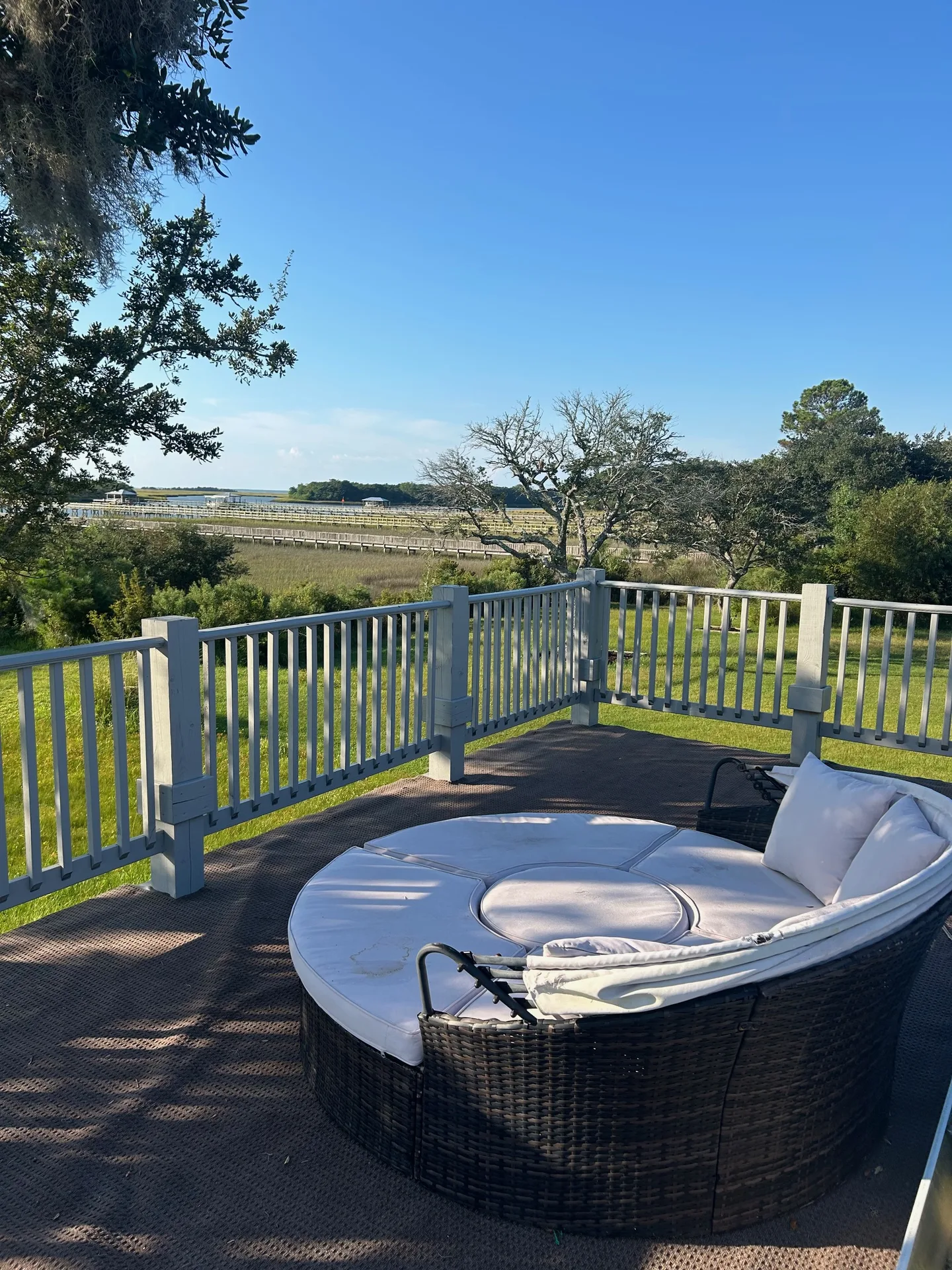 Elevated deck with round wicker daybed, retractable canopy, and sweeping marsh views