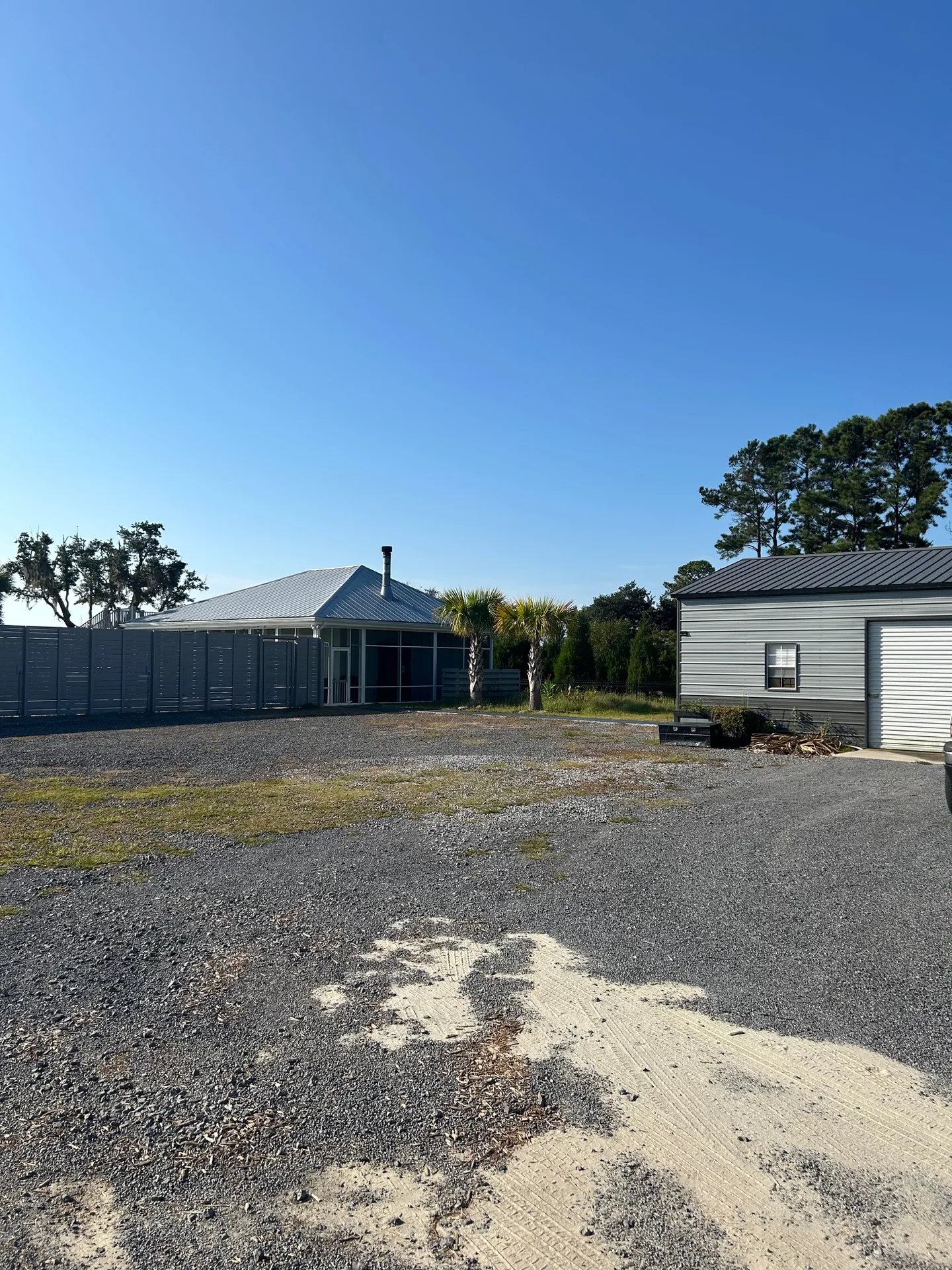 Compound exterior with screened pavilion, standing-seam roof, and outbuildings