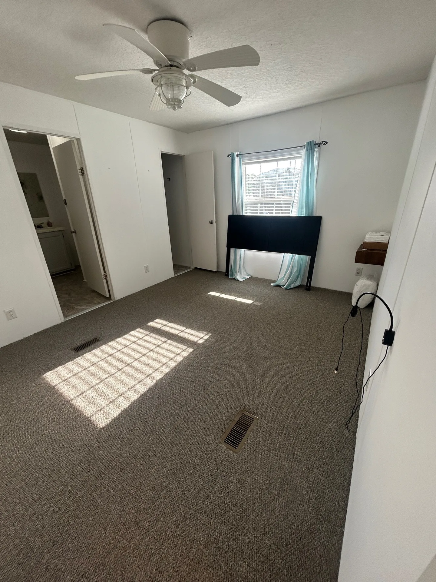 Guest bedroom with gray plaid comforter, neutral carpet, and ceiling fan