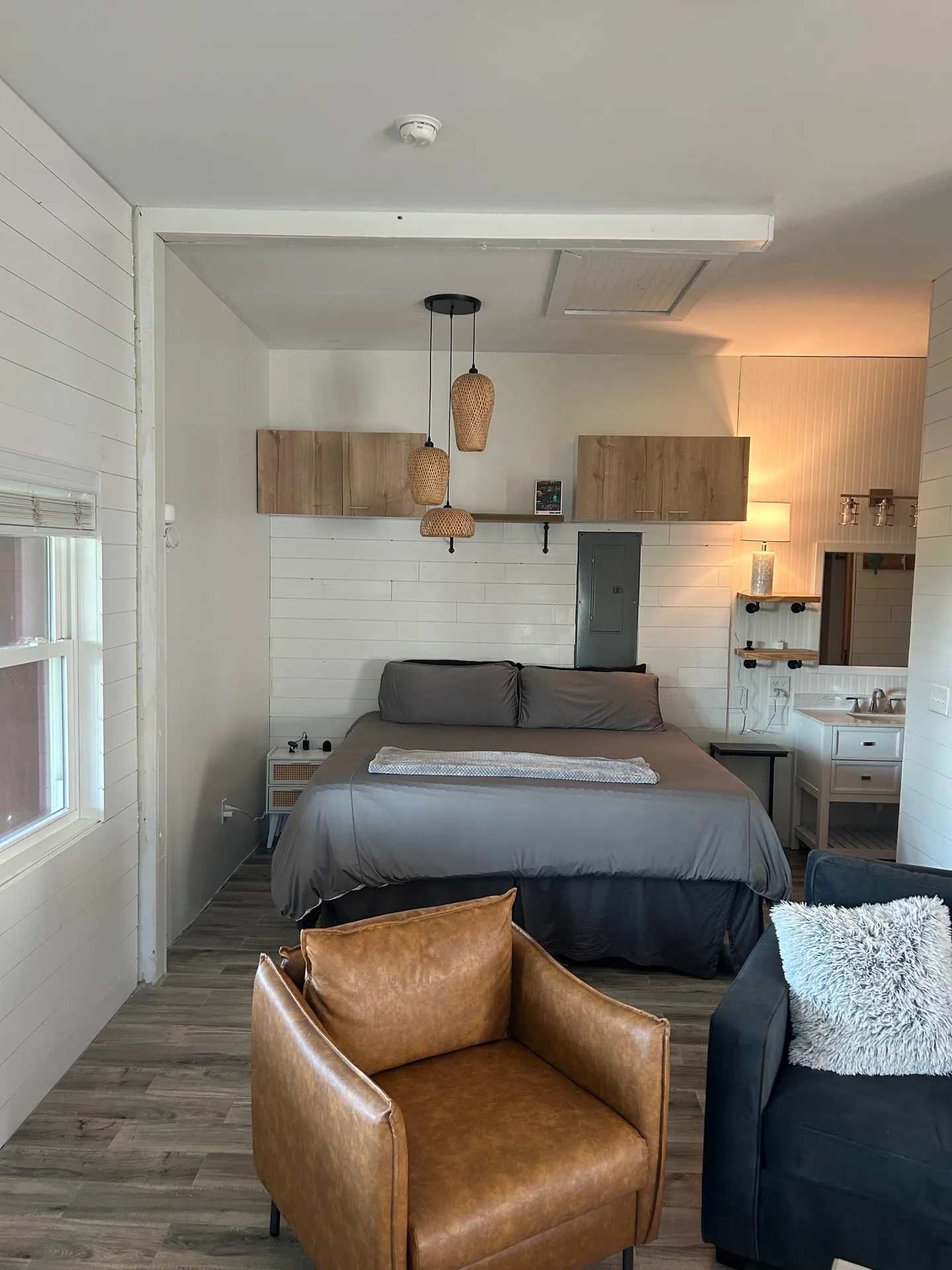 Bedroom and open bath with queen bed, rattan pendant lights, and walk-in shower