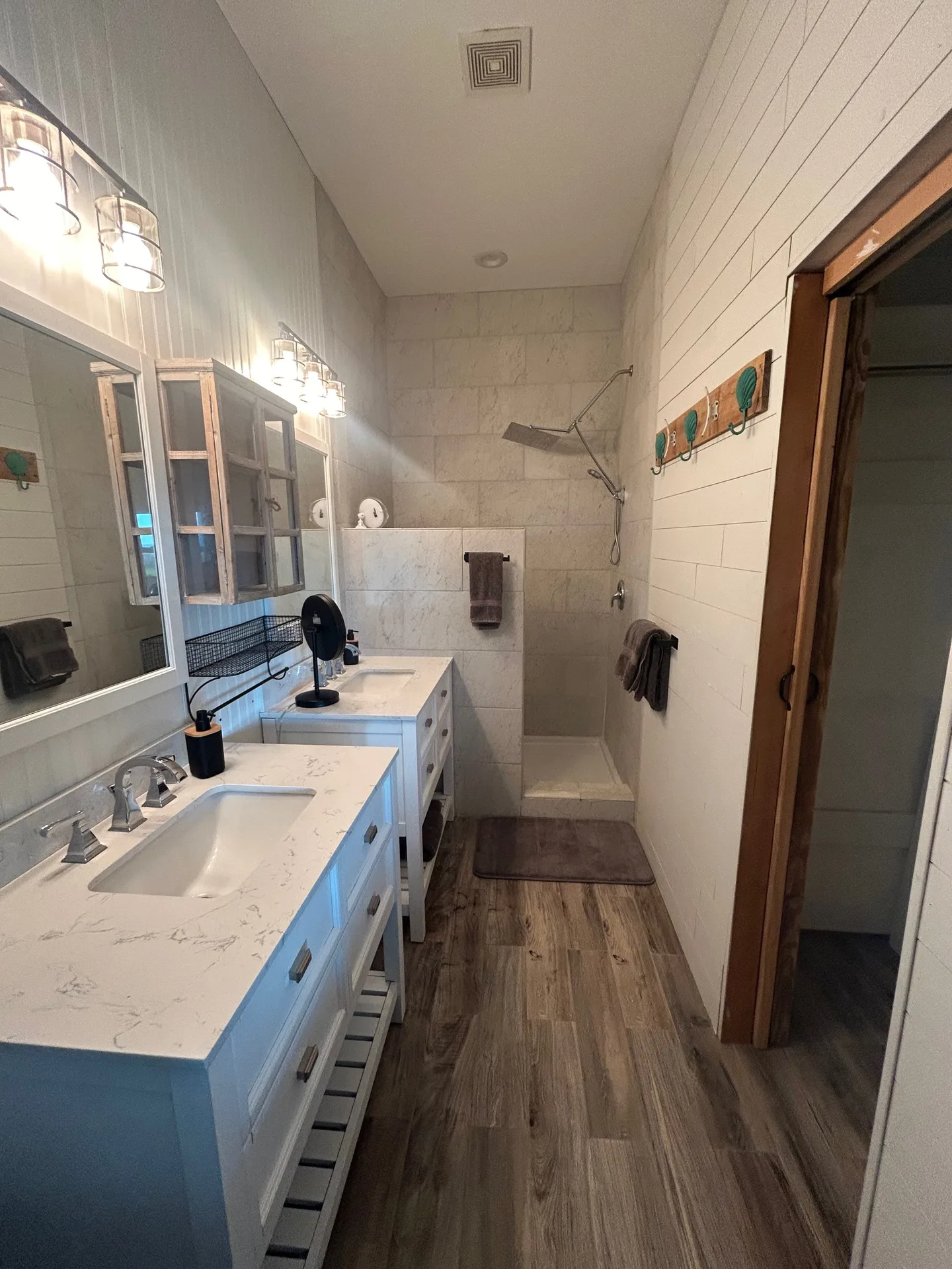Bathroom from vanity to shower with marble top, pipe shelving, and wood-look tile