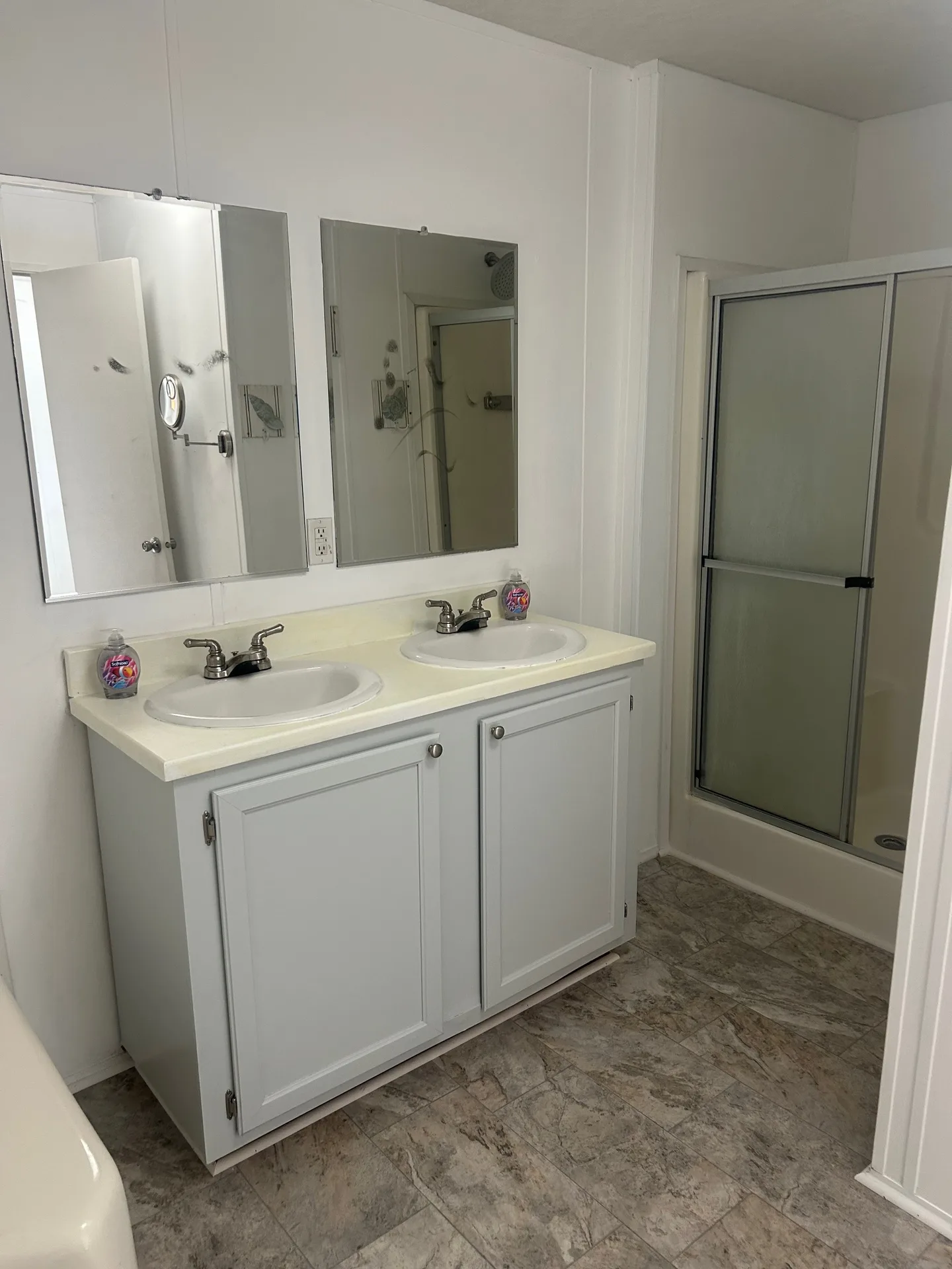 Bathroom with double vanity, frosted glass shower, and marble-look floor