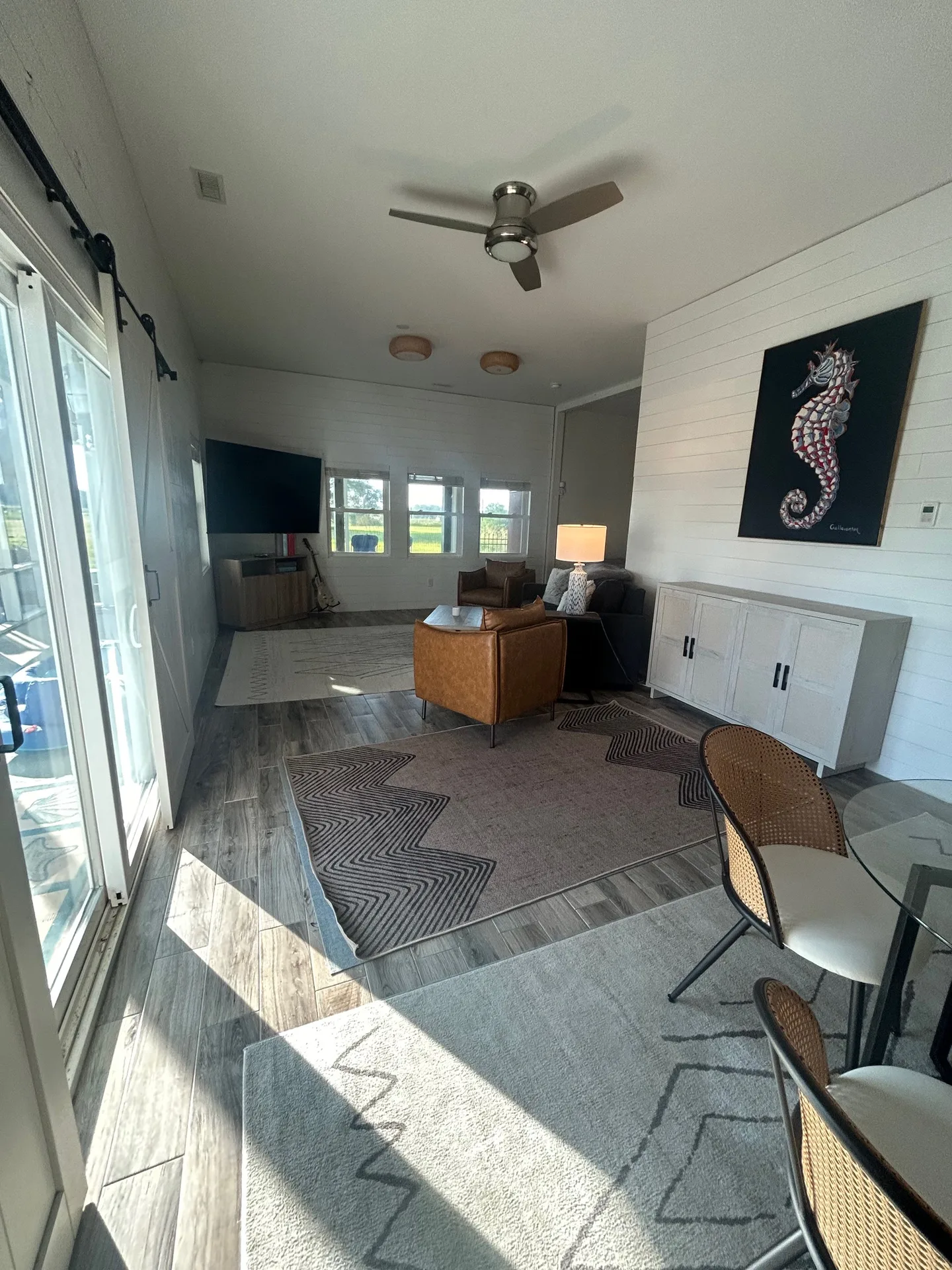 Living room with charcoal sofa, coral seahorse art on shiplap, and chevron rug